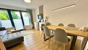 Una sala de estar moderna con un sofá, una mesa de comedor con sillas, un televisor y un radiador.