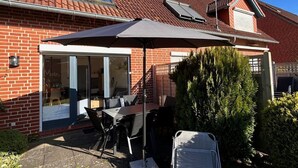 Una casa de ladrillo con un porche cubierto, una antena parabólica y un pequeño jardín.