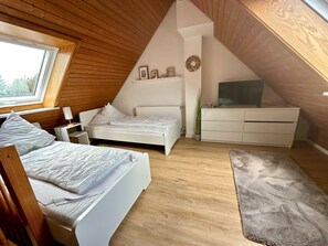 A bedroom with a sloped ceiling, a bed, a dresser, a TV, and a window. - 7033 House Wellengang - 7033 House Wellengang with large garden (Dahme)