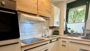 Una cocina moderna con armarios blancos, un horno negro y una ventana con persianas.