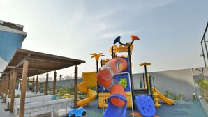 A children's play area with slides, climbing structures, and a seating area with benches. - Kratos Club (Surat)