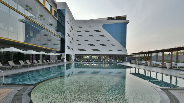 A modern hotel with a large indoor pool, lounge areas with sunbeds, and a distinctive architectural design. - Kratos Club (Surat)