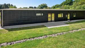 Ein modernes Gebäude mit flachem Dach, großen Fenstern und einer gepflasterten Eingangszone.