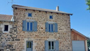 A stone building with two windows and a door, a chimney, and a small attached garage. - Armand's House (Yssingeaux)