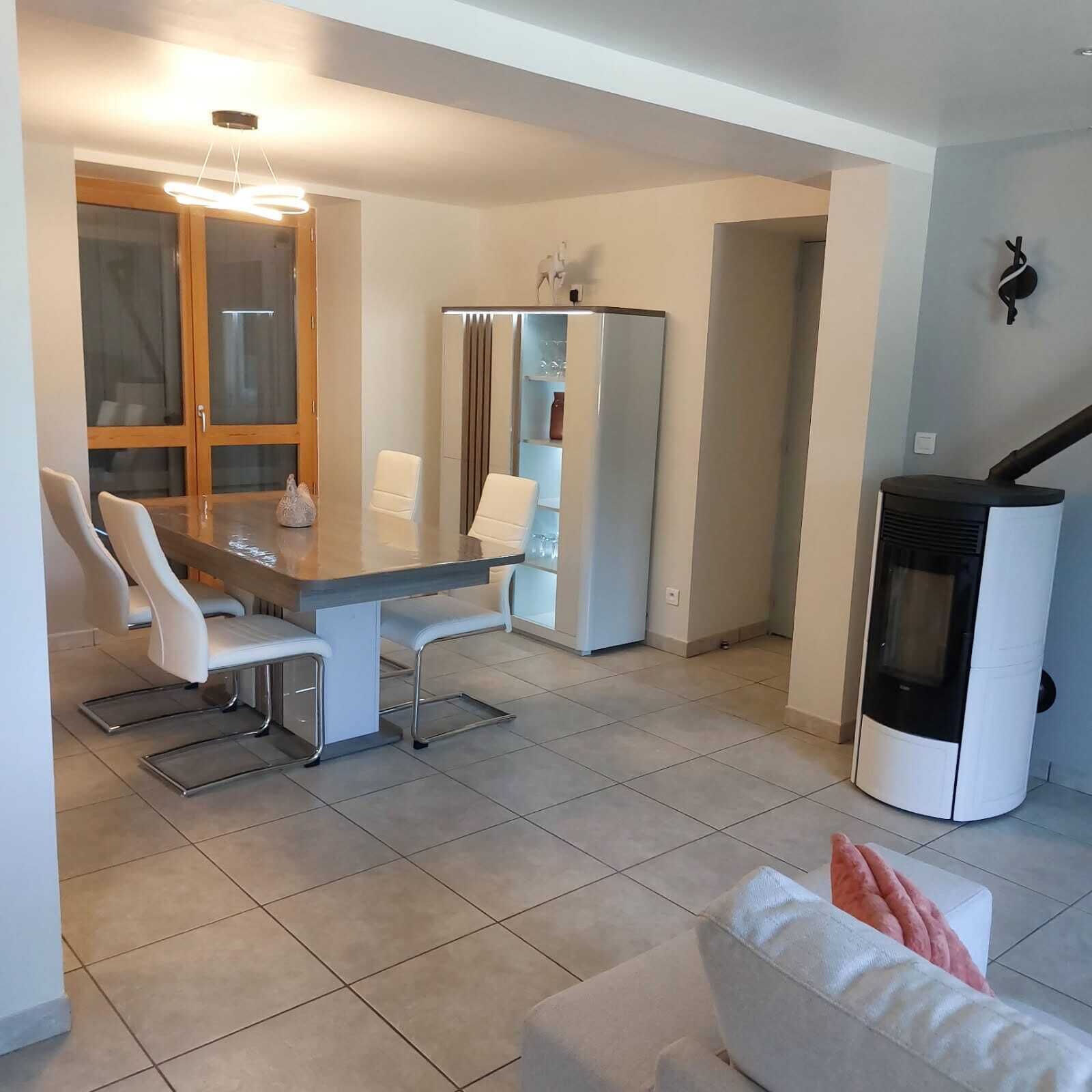 A modern living room with a dining area, a built-in kitchen, and a fireplace.