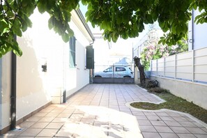 A paved pathway leading to a vehicle, surrounded by buildings and greenery.