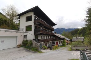 A multi-story building with a garage, wooden balconies, and a red door. - Cosy & Style Zell am See (Zell am See)
