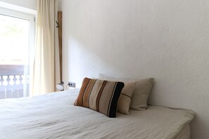 A neatly made bed with a striped pillow and a plain wall.