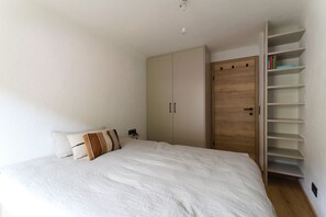 A bedroom with a bed, a wardrobe, and a built-in bookshelf.