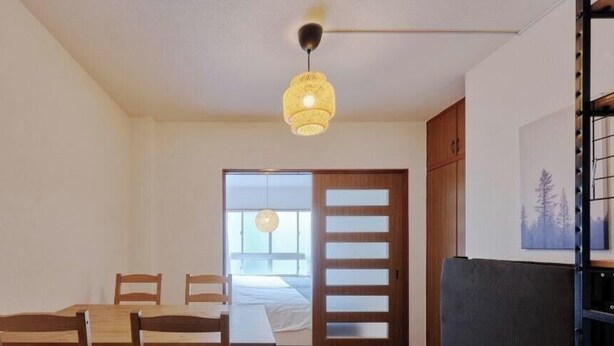 A room with a dining table and chairs, a sofa, a hanging light fixture, and a door leading to another room. - XS01 XROSS STAY Namba1 (大阪市)