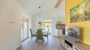 A modern living room with a dining area, wooden flooring, and a large painting on the wall. - Vacation home "Huus Mullewap" in Kating for up to 4 people (Kating)