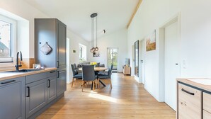 Una cucina moderna con mobili grigi, un piano di lavoro in legno e un'area pranzo con tavolo e sedie.