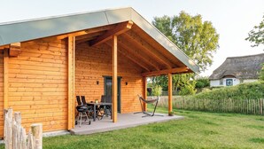 Una baita di legno con un portico coperto, un tavolo con sedie e un'amaca.