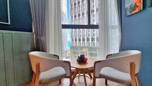A dining area with two chairs and a table, a window with a view of buildings, and a radiator on the wall.