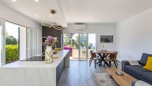 A modern kitchen with a marble countertop, a vase with flowers, and a dining area with a table and chairs.
