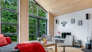Un salon moderne avec de grandes fenêtres, un canapé, une table basse et un téléviseur.