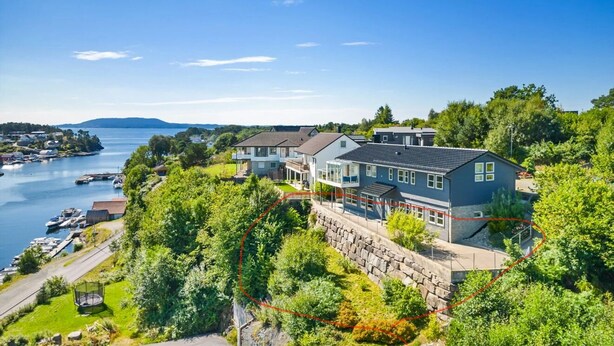 Ett stort hus med en stenmur och en balkong med utsikt över en sjö.