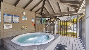 Ein Whirlpoolbereich mit Holzterrasse, überdachtem Dach und Schildern, die Spa- und Poolregeln erläutern.