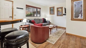 Ein Wohnzimmer mit einer Couch, einem Couchtisch und einem Essbereich mit einem Barhocker.