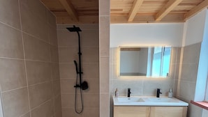 A modern bathroom with a shower, a sink, and a mirror. - Charming comfort room (Fénols)