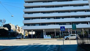 Un edificio de varios pisos con fachada plana, una señal de paso para peatones y una señal de estacionamiento.