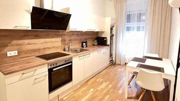 Una cocina moderna con mostradores de madera, horno empotrado y comedor con mesa y sillas.