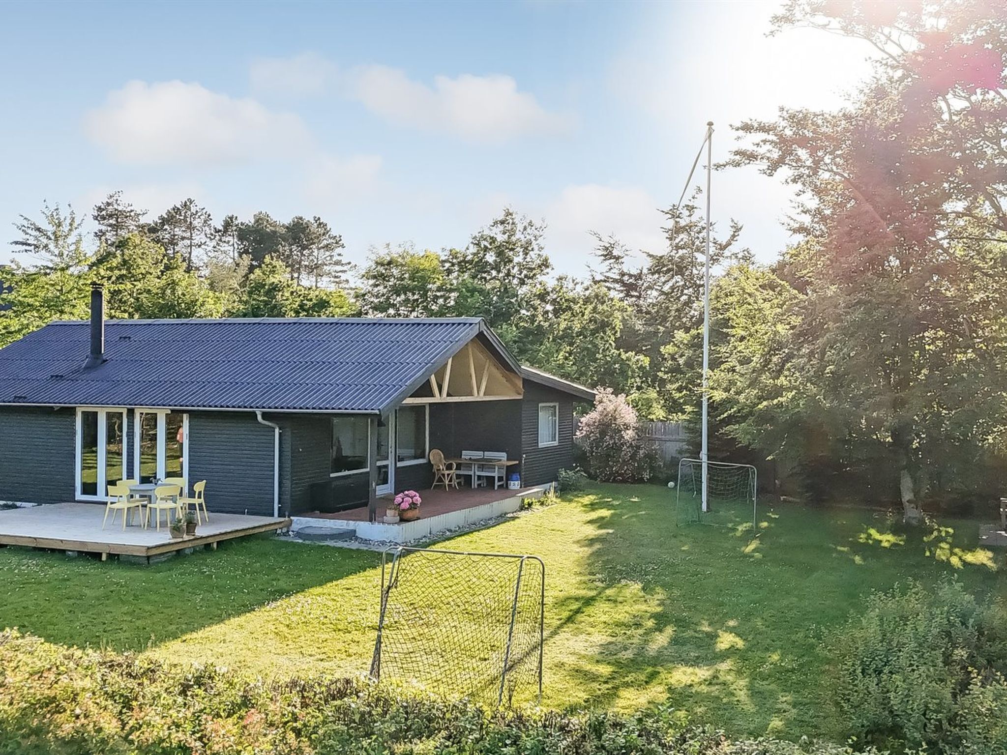 Ein kleines Haus mit Veranda, Rasen und einem Fußballtor.