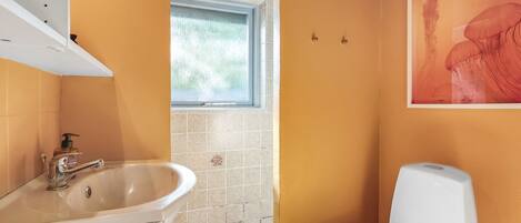A bathroom with a white sink, a toilet, and a window.