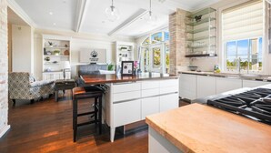 A modern kitchen with a central island, white cabinetry, and a large window providing natural light. - 2BR Penthouse w/ Balcony | Grand Traverse Commons (Traverse City)
