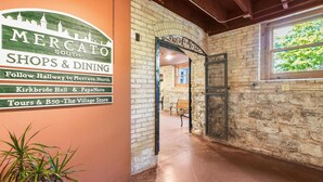 A corridor with a sign for Mercato South Shops & Dining, a bench, and a view of the outside. - 2BR Penthouse w/ Balcony | Grand Traverse Commons (Traverse City)