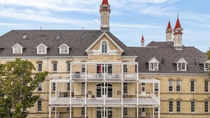 A historic building with a central tower, multiple chimneys, and a balcony. - 2BR Penthouse w/ Balcony | Grand Traverse Commons (Traverse City)