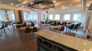 A spacious dining area with multiple tables and chairs, a central island with a marble countertop, and a modern ceiling design. - Comfortable rooms with kitchen - perfect for relaxation, work and exchange (Winterberg)