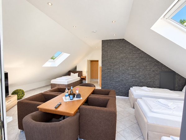 A modern hotel room with a dining area, a separate sleeping area, and a skylight.