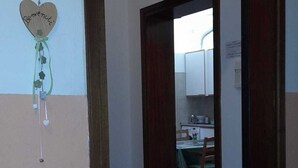 A hallway leading to a kitchen area with cabinets and a dining table. - Appartamentino vicino alla Stazione ed al Centro (Padova)