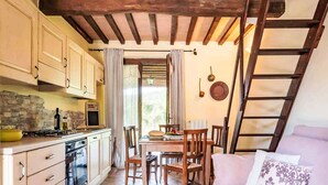 A cozy kitchen with wooden cabinets, a stove, and a dining area with a table and chairs. - Agriletizia by Interhome (Massa Marittima)