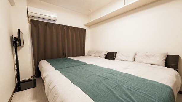A hotel room with a bed, a TV, and an air conditioning unit. - 2 double beds, free Wi-fi, can accommodate up to 4 people 【ANY INN FUKUOKA NANAKUMA (福岡市)