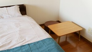 A bed with white and blue bedding, a wooden nightstand, and a brown stool in a room with wooden flooring and white walls. - 2 double beds, free Wi-fi, can accommodate up to 4 people 【ANY INN FUKUOKA NANAKUMA (福岡市)