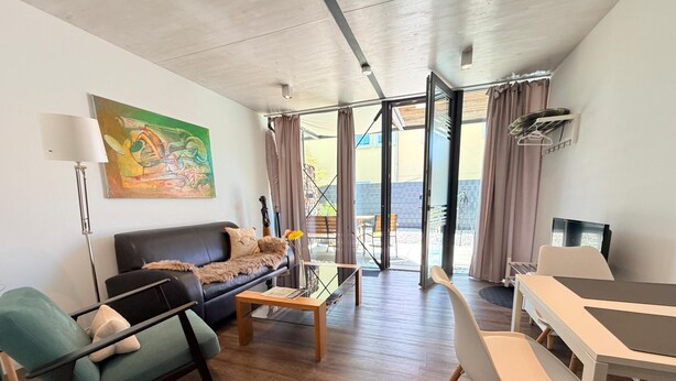 Ein modernes Wohnzimmer mit Sofa, Couchtisch und Essbereich.