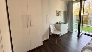 Ein modernes Schlafzimmer mit großem Kleiderschrank, Schreibtisch mit Schubladen, Stuhl und Bett.