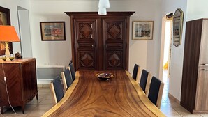 A long wooden dining table with chairs, a bowl, and a cabinet with decorative panels. - Vacation home with pool (Agde)