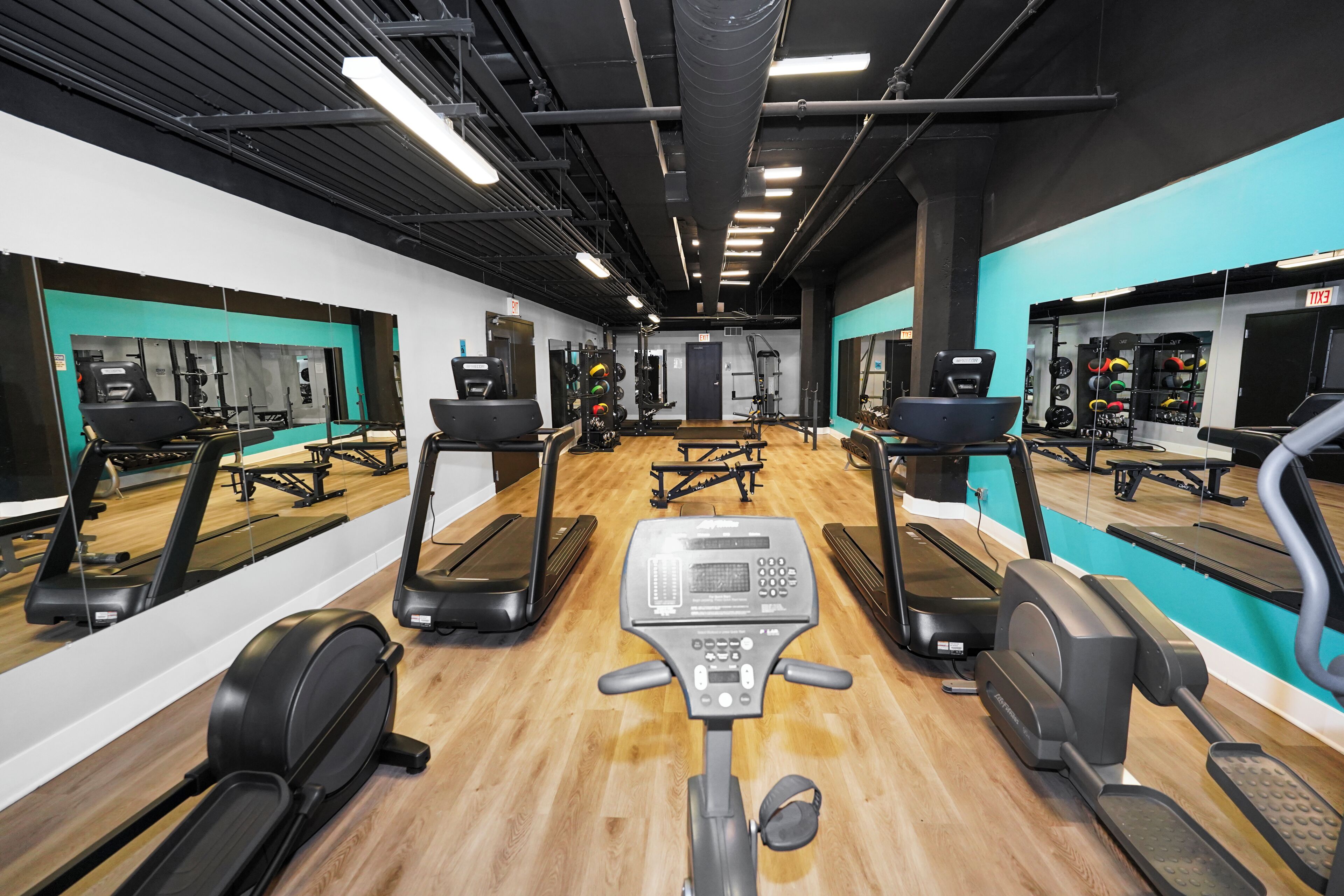 A gym with treadmills, elliptical machines, and weightlifting equipment.