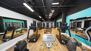 Un gimnasio con cintas de correr, elípticas y equipo de levantamiento de pesas.