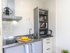Een koelkast, een microgolfoven, een oven, kookgerei, borden en bestek