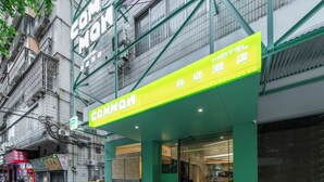 Un hôtel appelé «COMMON», avec une façade d’un vert vif et un panneau lumineux au néon.