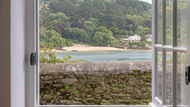 Une vue à travers une porte, avec un mur de pierre et une plage en arrière-plan.