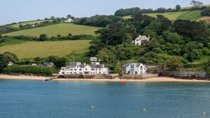 Une propriété située sur la côte, avec une plage, une jetée et des maisons construites sur une colline.