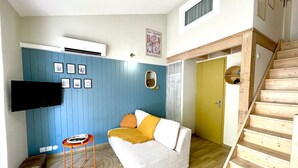 A living room with a white sofa, a blue wall, and a wooden staircase.
