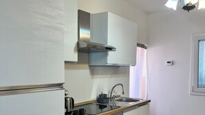 A modern kitchen with white cabinets, a stainless steel range hood, a built-in oven, and a wooden countertop. - La Rosa - Comfort & Charm in the Town Center (Monselice)
