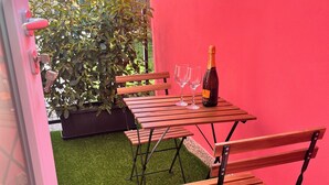 A patio with a table, two chairs, a bottle of champagne, and a potted plant. - La Rosa - Comfort & Charm in the Town Center (Monselice)