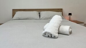 A neatly made bed with striped bedding and two pillows, a rolled white towel, and a bedside lamp on a wooden nightstand. - La Rosa - Comfort & Charm in the Town Center (Monselice)